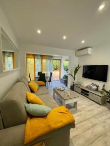 a living room with a couch and a flat screen tv at A1 LA PLAGE D'OR in Le Lavandou