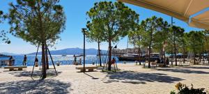 einen Strand mit Bänken und Bäumen neben dem Wasser in der Unterkunft Apartment Alex in Sarandë
