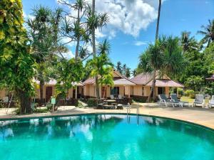 a swimming pool in front of a house with palm trees at Salatan Resort in Ko Lanta