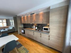 a kitchen with wooden cabinets and a living room at Skjomtind - Modern apartment with free parking in Narvik