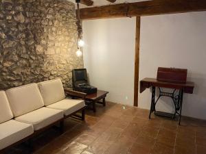 een woonkamer met een bank en een bureau met een laptop bij Masía La Perera in Morella