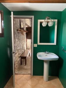 baño verde con lavabo y banco en Masía La Perera, en Morella