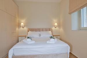 a bedroom with a large white bed with two towels at EFMAR EXCLUSIVE RESIDENCES in Gythio