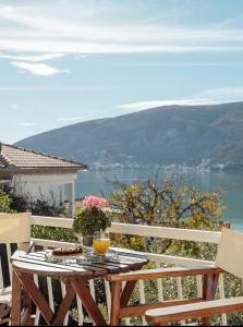 uma mesa com um copo de sumo de laranja numa varanda em Apartmani Vico em Herceg Novi