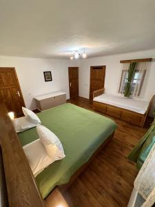 1 dormitorio con 1 cama verde grande y suelo de madera en Haus Ingrid Cisnadioara, en Cisnădioara