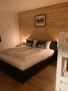 a large bed in a bedroom with a wooden wall at Alpenhaus Bichlbach in Bichlbach