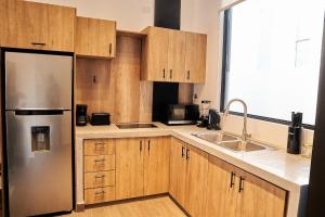 a kitchen with wooden cabinets and a stainless steel refrigerator at AmazINN Places Rooftop and Design Pool II in Panama City