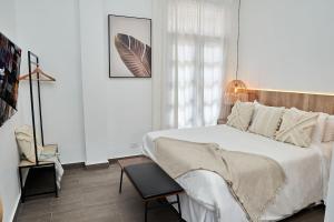 a white bedroom with a bed and a chair at AmazINN Places Rooftop and Design Pool III in Panama City