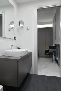 ein Badezimmer mit einem Waschbecken, einem Spiegel und einem Stuhl in der Unterkunft The Lop Athens Holidays Luxury Suites in Athen