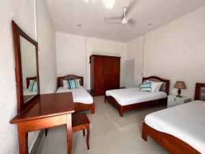 a room with two beds and a desk and a mirror at Gaskara Guesthouse in Shaviyani Atoll