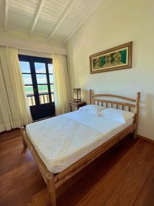 um quarto com uma cama com uma estrutura em madeira em Casa Rio - 04 Quartos de Frente para o Mar em Guarda do Embaú