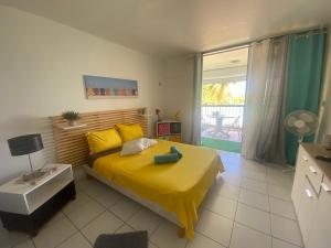 ein Schlafzimmer mit einem Bett mit einer gelben Decke darauf in der Unterkunft OCEANE 2 in Le Gosier
