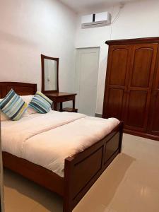 1 dormitorio con 1 cama grande y armario de madera en Gaskara Guesthouse, en Shaviyani Atoll