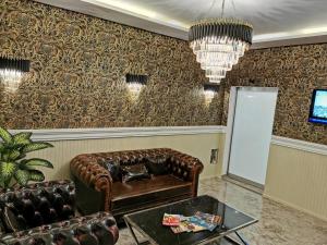 a living room with a leather couch and a chandelier at Marrakeschotel in Tuzla