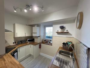 a kitchen with white cabinets and a sink and a window at Large Three bed Two bathroom flat in Central Torquay in Torquay