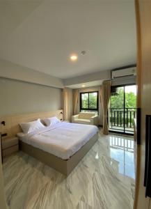 a bedroom with a bed and a couch and windows at Baan Thanakul Residences in Samutprakarn