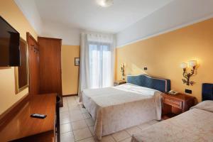 モンテカティーニ・テルメにあるHotel Salusのベッド2台とテレビが備わるホテルルームです。