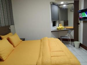 a bedroom with a large yellow bed and a television at SMART Dream Inn in Tangerang