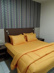 a bed with yellow sheets and pillows in a bedroom at SMART Dream Inn in Tangerang