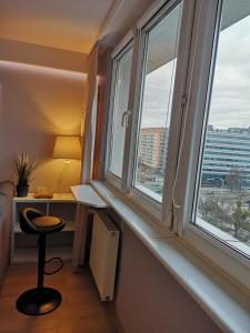 Habitación con 2 ventanas, escritorio y silla. en Apartament 8 Piętro Al Wyzwolenia, en Szczecin