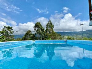 une piscine avec de l'eau bleue et des montagnes en arrière-plan dans l'établissement Finca Villa Maju, à Papagalleros