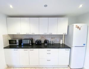 a kitchen with white cabinets and a white refrigerator at Central 4 bed-Reading City Centre in Reading