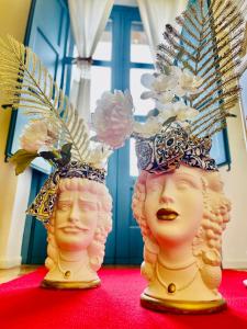 dos estatuas de cabezas usando sombreros en una alfombra roja en Casale Di Benedetto en Caltagirone