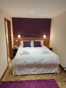 a bedroom with a large white bed with purple pillows at The King Alfred in Street