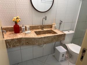 a bathroom with a sink and a toilet and a mirror at Pousada Beija Flor in Maceió