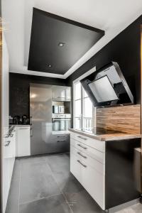una cocina con armarios blancos y una pared negra en Disneyland-Dream 8 pers,2 parking, Wifi, Netflix, en Serris