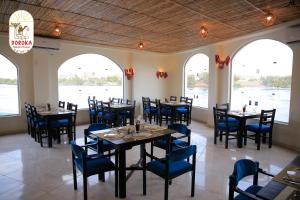 uma sala de jantar com mesas, cadeiras e janelas em DoroKa Nubian House em Shellal