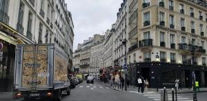 ein LKW, der eine Stadtstraße mit Gebäuden entlangfährt in der Unterkunft HAUSSMANN ESPACE in Paris + 10 Fotos