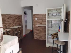 Habitación vacía con nevera abierta y taburetes en Casa Toda, en São Vicente