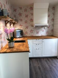uma cozinha com armários brancos e papel de parede floral cor-de-rosa em Annehill i Bro em Bro