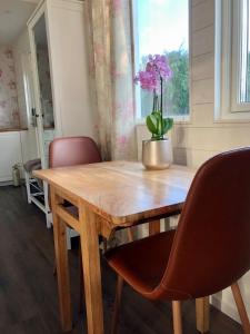 una mesa de madera con sillas y un jarrón de flores. en Annehill i Bro en Bro