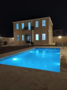 a large swimming pool in front of a house at night at Mardakan Villa in Baku