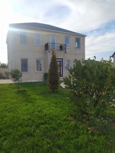 una grande casa bianca con un cortile verde di Mardakan Villa a Baku