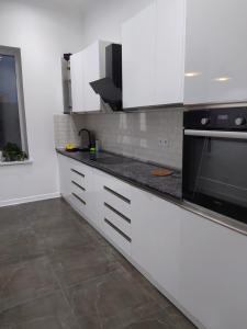 a kitchen with white cabinets and a black microwave at Mardakan Villa in Baku