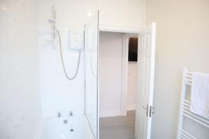 a white bathroom with a shower and a sink at Twelve Thirty Serviced Apartments - 2 Croydon in South Norwood
