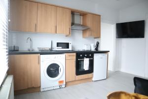 a kitchen with a washing machine and a microwave at Twelve Thirty Serviced Apartments - 2 Croydon in South Norwood