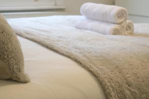a bed with white towels on top of it at Twelve Thirty Serviced Apartments - 2 Croydon in South Norwood