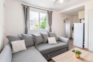 a living room with a gray couch and a window at FERY HOME 76 - Au Paradis Caché de Rouen in Notre-Dame-de-Bondeville