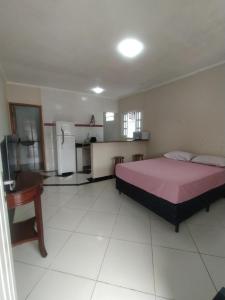 a bedroom with a bed and a table and a kitchen at Bertioga litoral in Bertioga