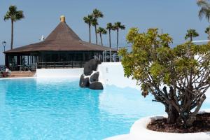 una piscina en un complejo con un árbol en el medio en Apartment in South Tenerife with heated pool, en Costa del Silencio