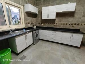 uma cozinha com armários brancos, um lavatório e uma máquina de lavar louça em فلل نادي الصيد em Cidade 6 de Outubro