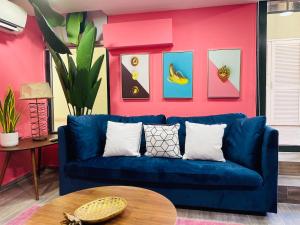 a blue couch in a living room with a pink wall at AmazINN Places Casco Viejo Pink Desing and Pool IX in Panama City