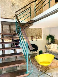 a living room with a staircase and a yellow chair at AmazINN Places Casco Viejo Duplex and Pool in Panama City