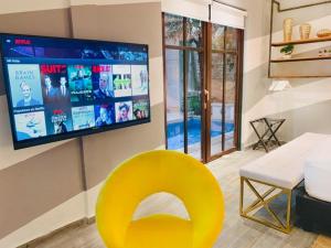 a yellow chair in a living room with a tv at AmazINN Places Casco Viejo unique Desing and Pool VII in Panama City