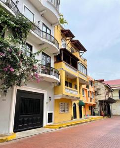 a yellow and white building with balconies on a street at AmazINN Places Casco Viejo Casa Espanola in Panama City