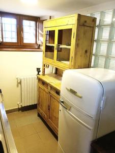 uma cozinha com um frigorífico branco e um armário de madeira em La Fioraia bilocale con giardino em LʼAquila